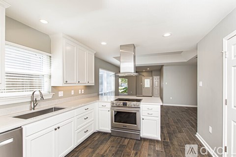 A modern kitchen with white cabinets and stainless steel appliances.