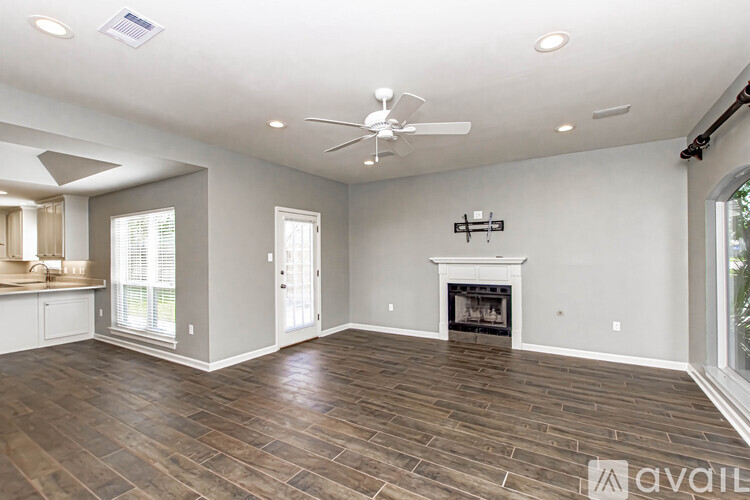 A spacious living room with wood flooring and a fireplace.