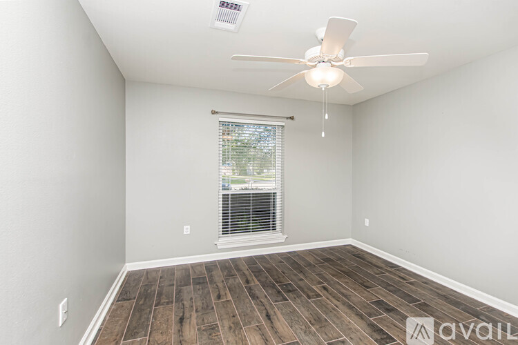 A room with a ceiling fan and wooden flooring.