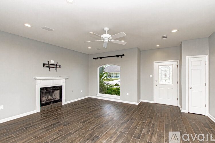 A spacious room with a fireplace and a fan on the ceiling.