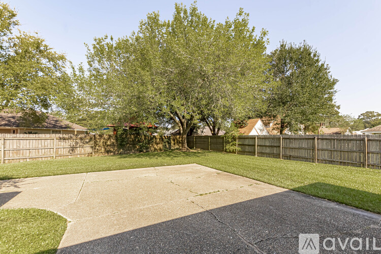 A backyard with a concrete patio and a large tree.