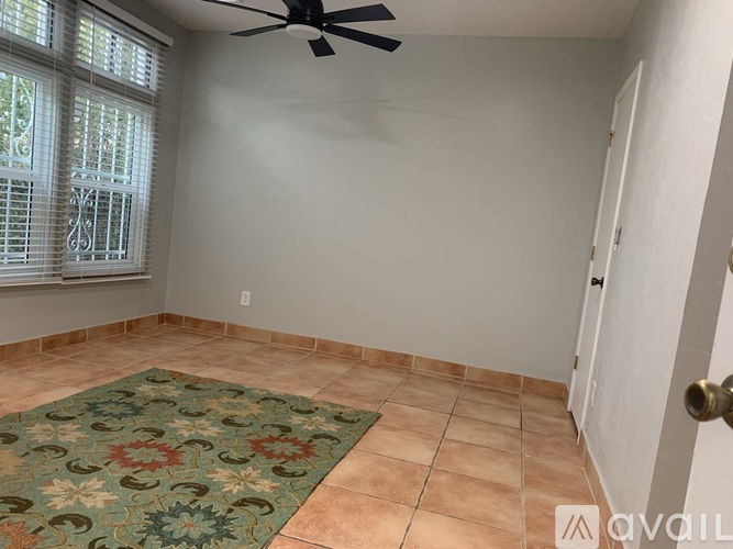 A room with a ceiling fan, tiled floor, and a rug.