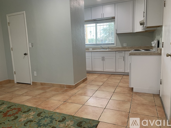 A kitchen with white cabinets and a tile floor.