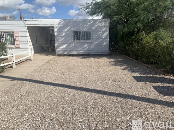 A white building with a gravel driveway in front.