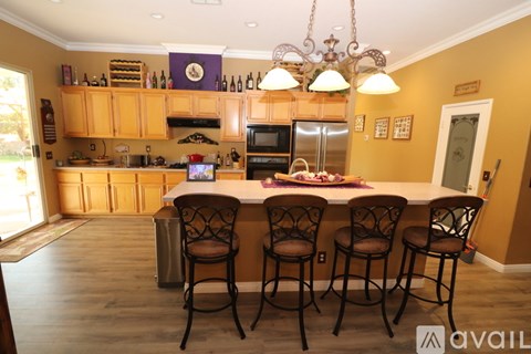 A kitchen with wooden cabinets and a white island with three chairs.