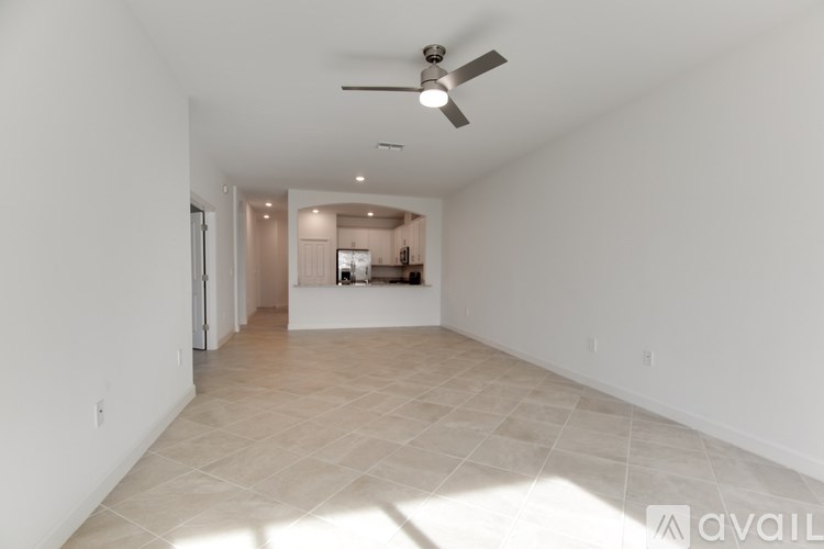 A spacious empty room with tiled flooring and white walls.