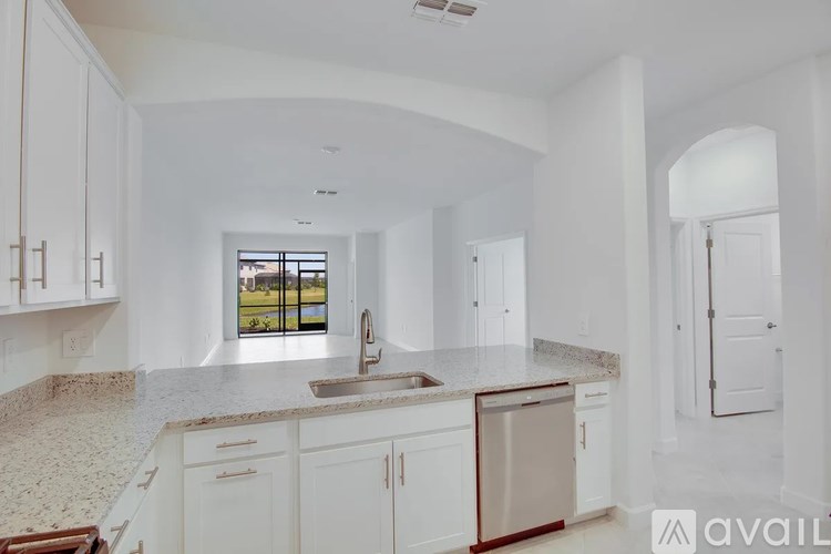 A kitchen with white cabinets and a marble countertop.