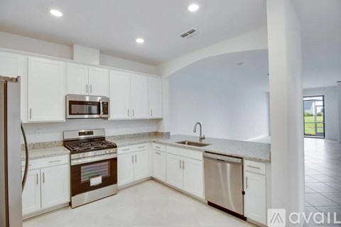 A kitchen with white cabinets and a stainless steel stove top oven.