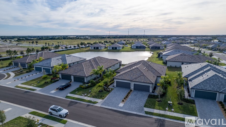 A white car is parked on the street in front of a house.