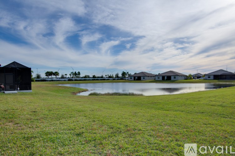 A grassy field with a house and a water body in the distance.