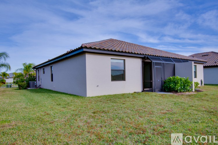 A house with a brown roof and a grey exterior is surrounded by a grassy lawn.
