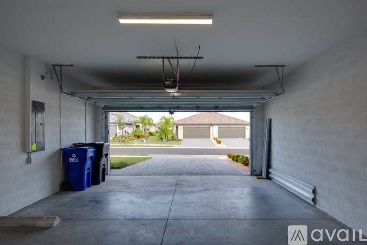 A long white garage door with a blue trash can underneath it.