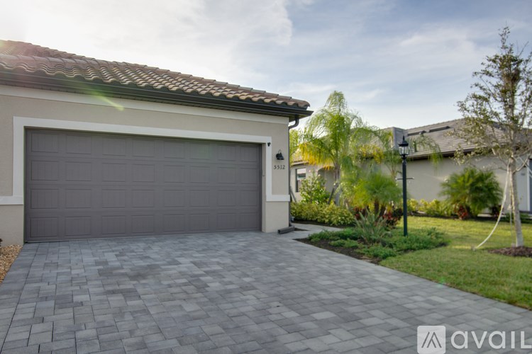 A house with a grey garage door and a driveway made of grey tiles.