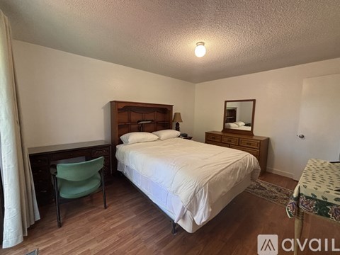 A bedroom with a bed, chair, and mirror.