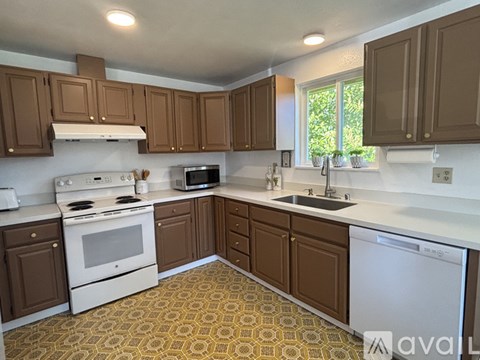 A kitchen with brown cabinets and a white stove top oven.