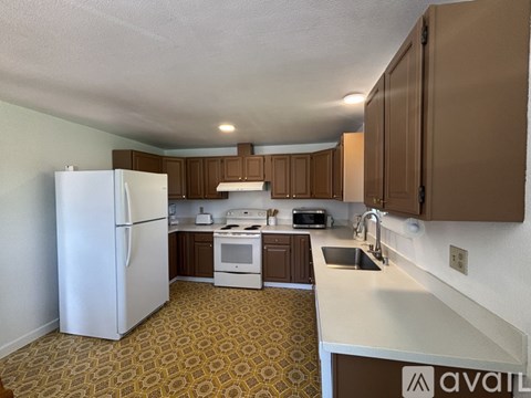 A kitchen with a white refrigerator, white stove, and brown cabinets.