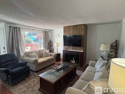 A living room with a blue chair, a couch, a coffee table, and a fireplace.
