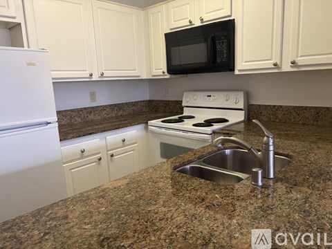 A kitchen with granite countertops and white appliances.