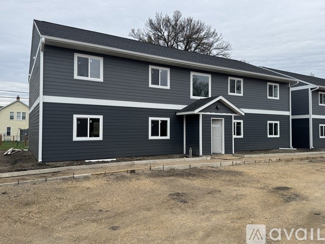 A two-story house with a grey exterior and white trim is under construction.