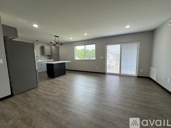 A spacious living room with a kitchenette and sliding glass doors.