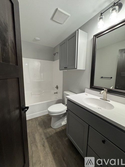A bathroom with a toilet, sink, and mirror.