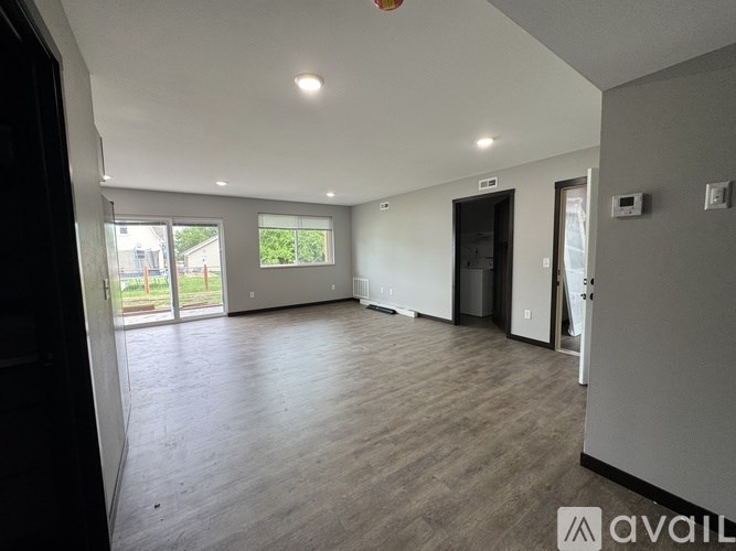 A spacious room with wooden flooring and white walls.