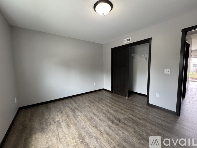 A room with a wooden floor and a door leading to another room.