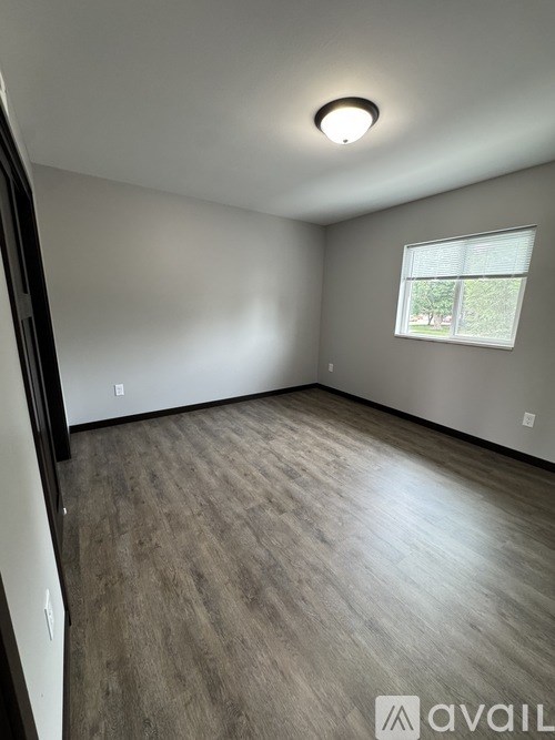 A room with a window and wooden flooring.