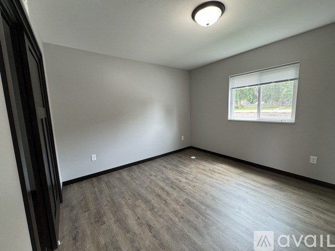 A room with a window and a wooden floor is available for rent.