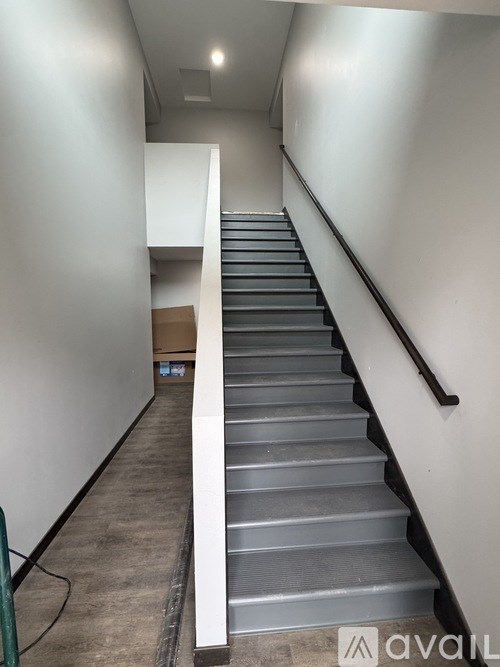 A staircase with a metal railing and grey steps.