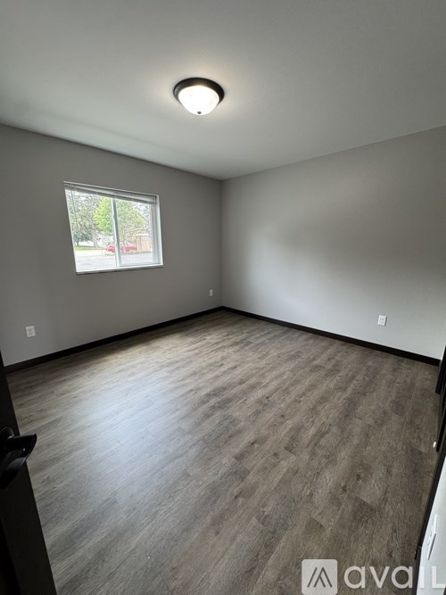 A room with a window and wooden flooring.