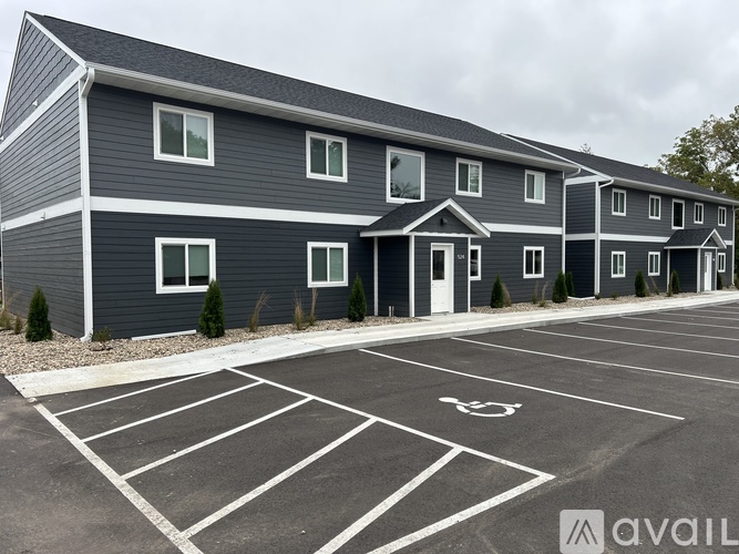 A parking lot with a handicap parking space in front of a grey building.