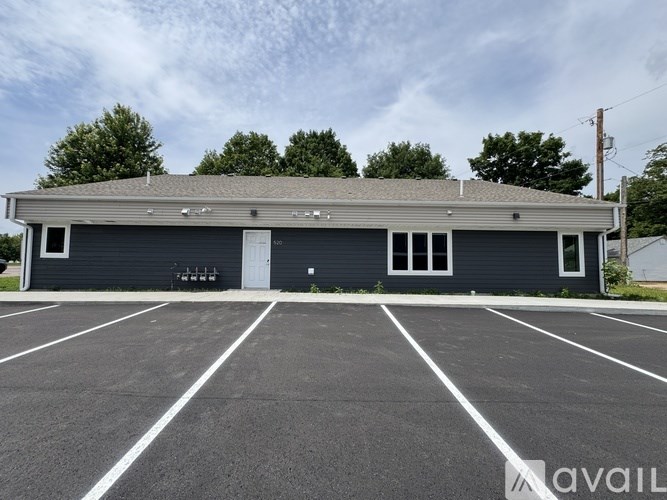 A building with a grey roof and a parking lot in front.