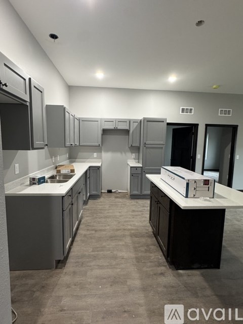 A kitchen with grey cabinets and a black counter top.