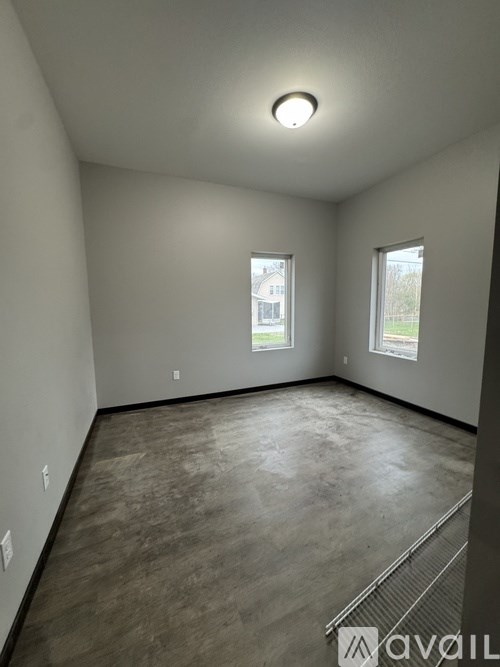 A spacious room with a window and a view of a house across the street.