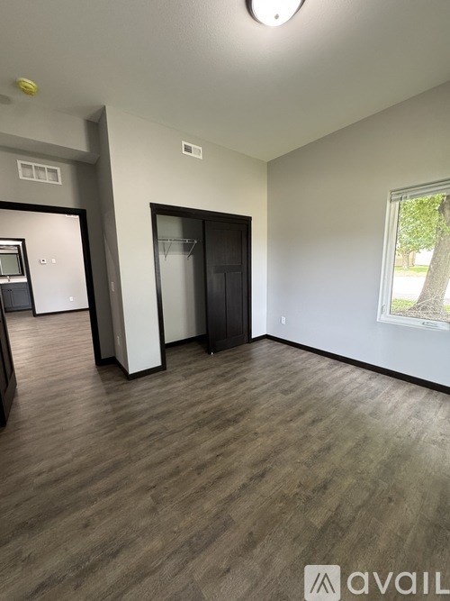 A room with a wooden floor and a window showing greenery outside.