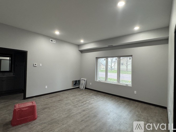 A room with a red chair and a window with a view of trees.