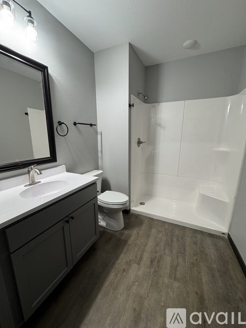 A bathroom with a toilet, sink, mirror, and shower.