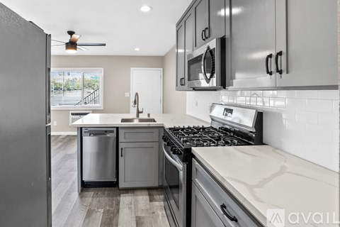 A modern kitchen with a stainless steel refrigerator and a black stove top.