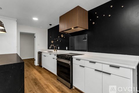 A modern kitchen with white cabinets and a black countertop.
