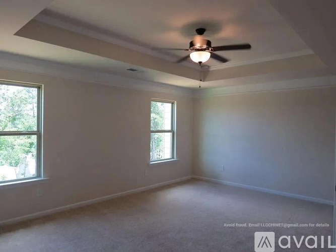 A room with a ceiling fan and two windows.