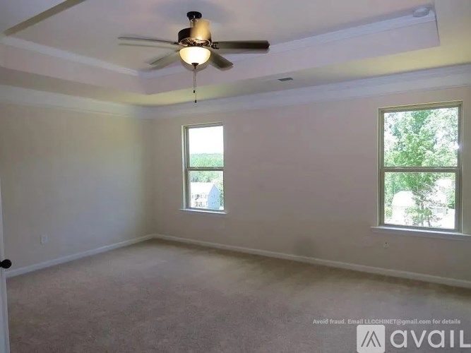 A room with a ceiling fan and two windows.