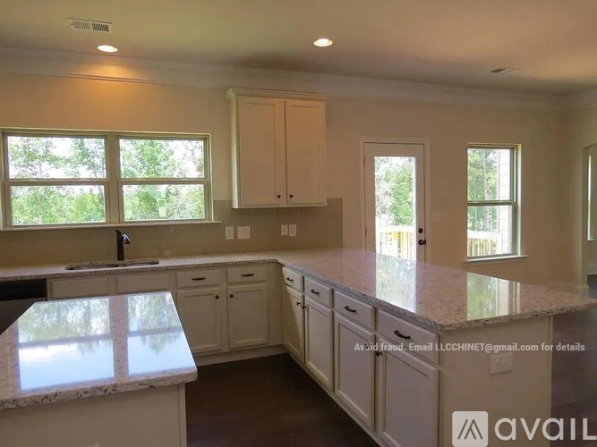 A kitchen with white cabinets and a marble countertop.