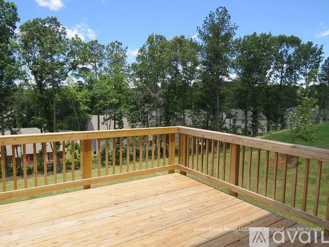 A wooden deck with a railing and trees in the background.