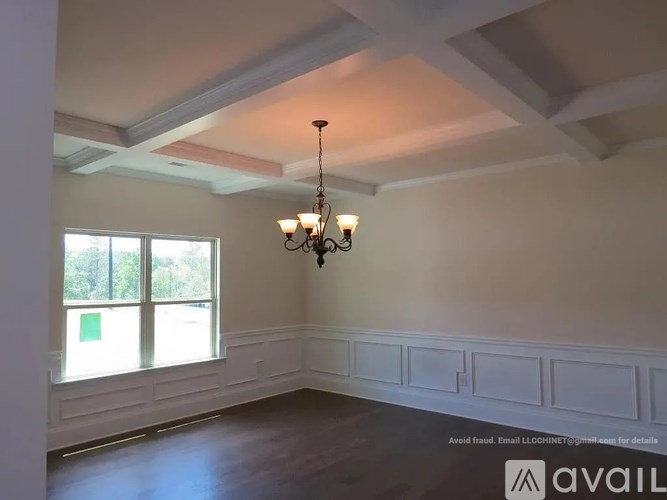 A room with a chandelier and a window with a view of trees.
