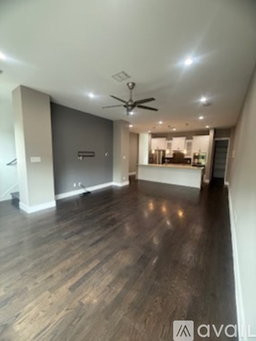 A spacious room with wooden flooring and a ceiling fan.