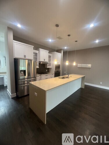 A modern kitchen with a central island and pendant lights.