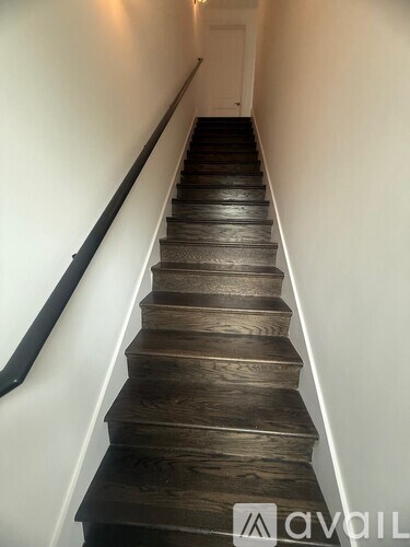 A staircase with wooden steps and a black handrail.