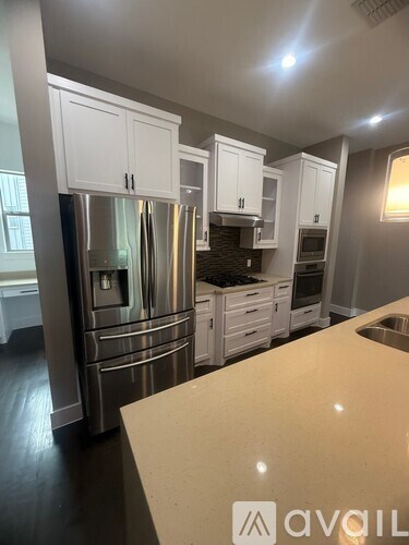 A kitchen with white cabinets and a stainless steel refrigerator.