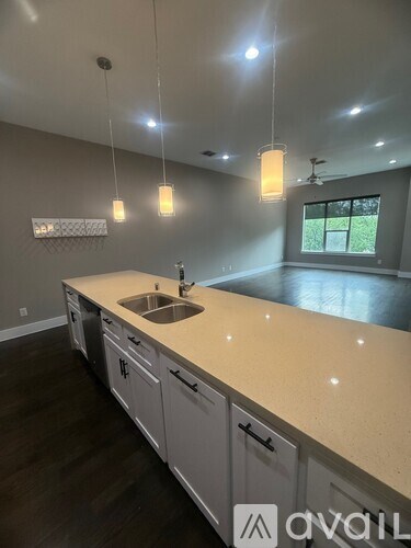 A kitchen with a sink and cabinets under a window.
